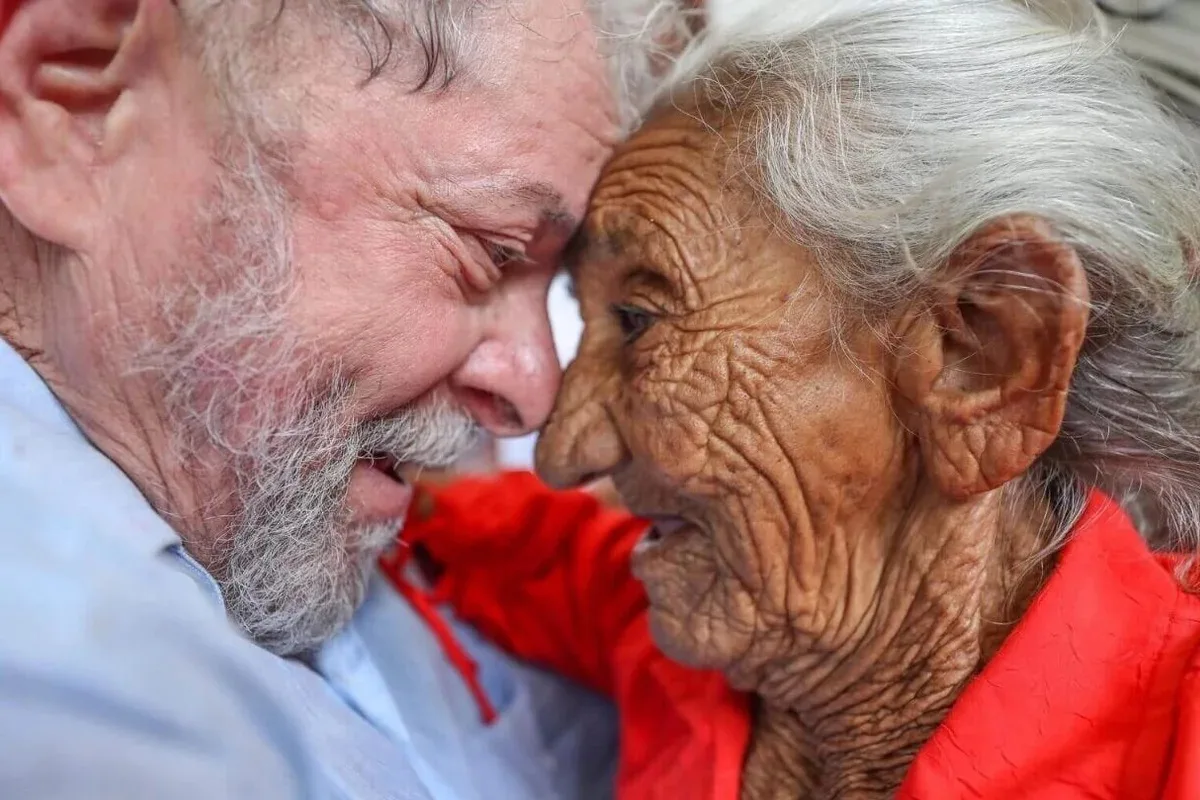 Lula sorrindo com cabeça próxima à de idosa