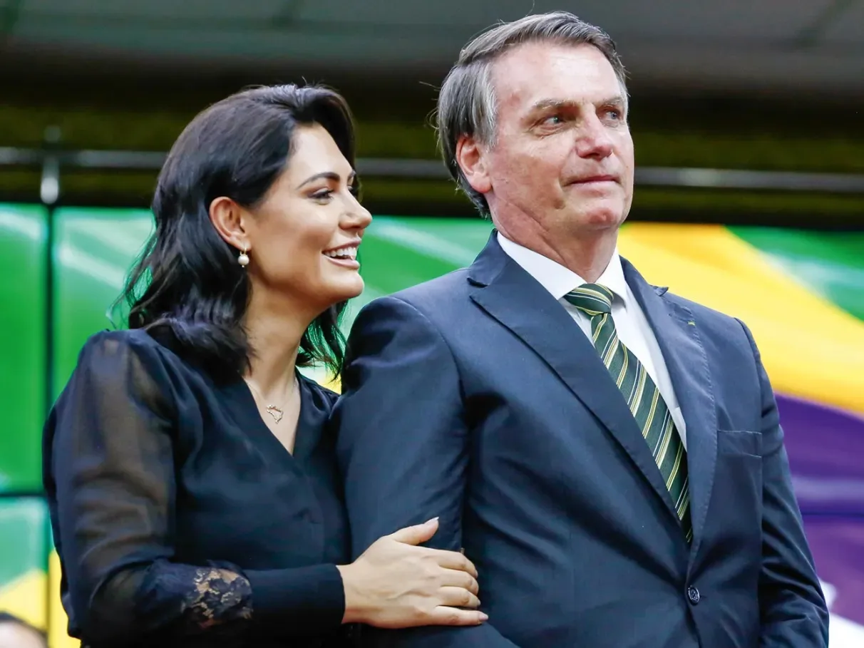 Michelle Bolsonaro sorrindo e Jair Bolsonaro sério